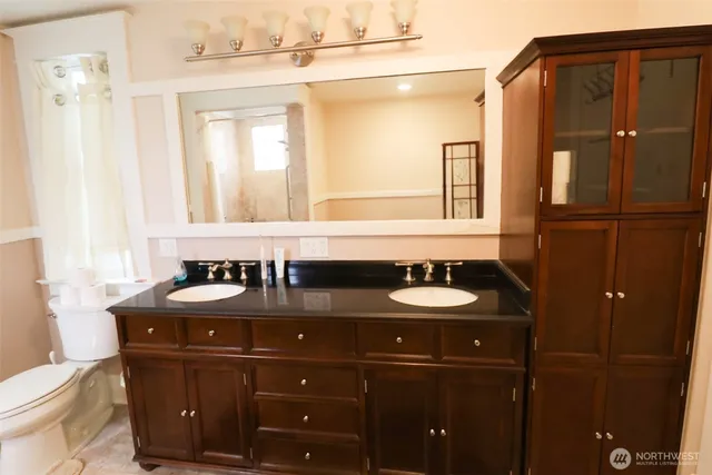 a bathroom with a granite countertop sink a toilet and mirror