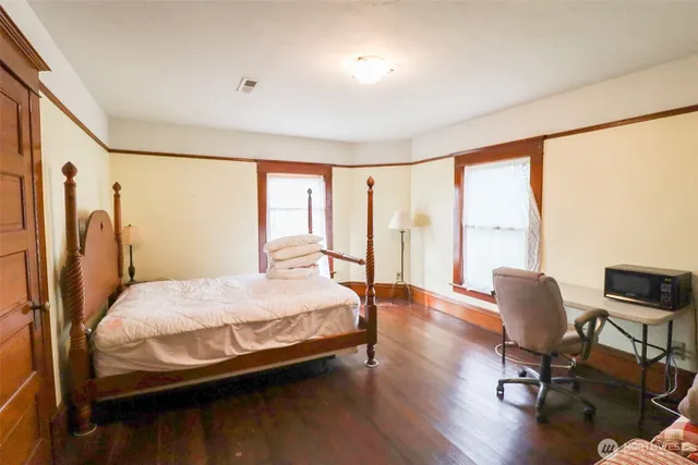 a bedroom with a bed and wooden floor