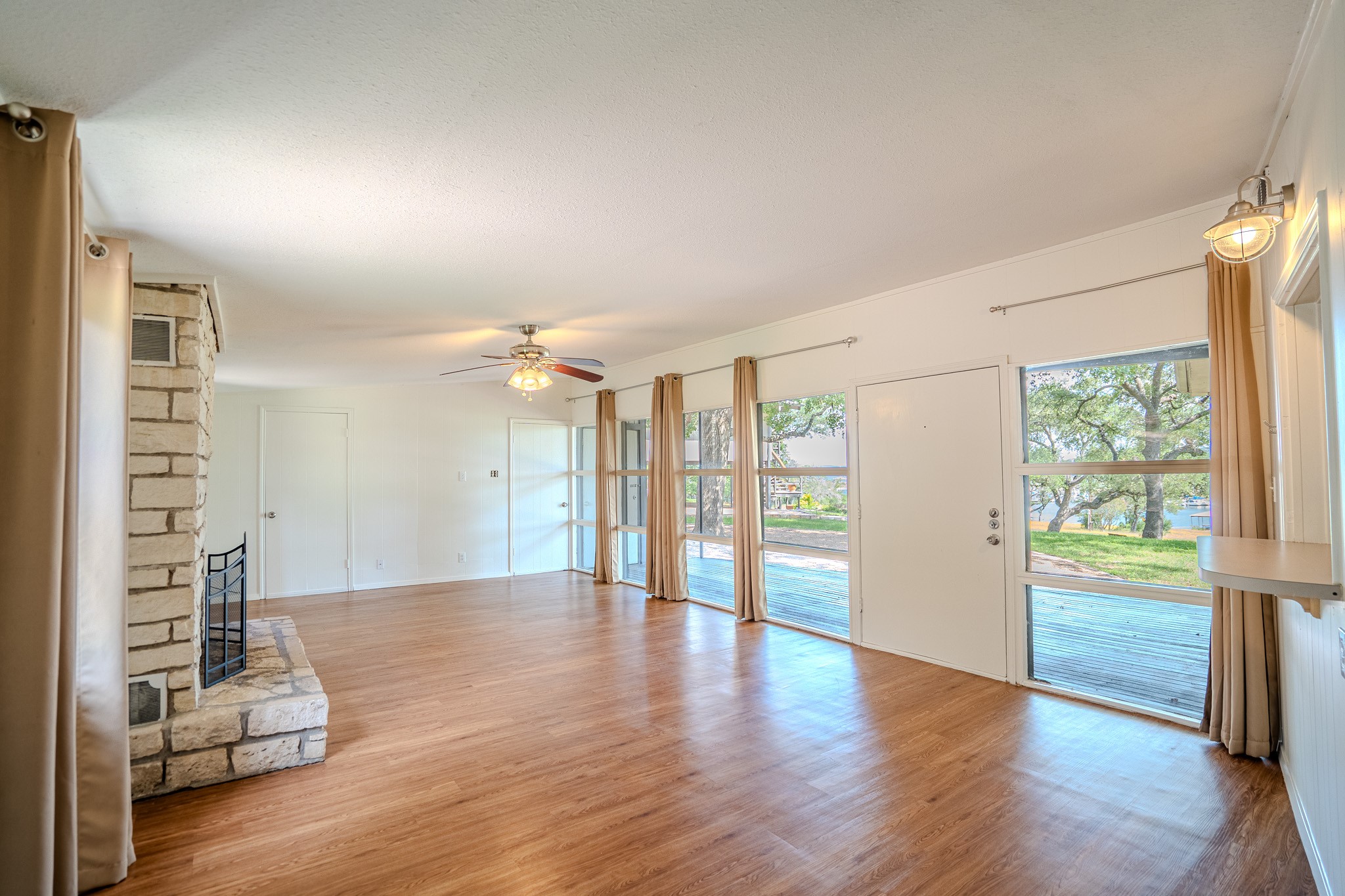 16013 Edwards Drive Austin, TX 78734 - Photo 5 of 18 A spacious living area boasts a stone fireplace and multiple windows overlooking serene outdoor greenery.