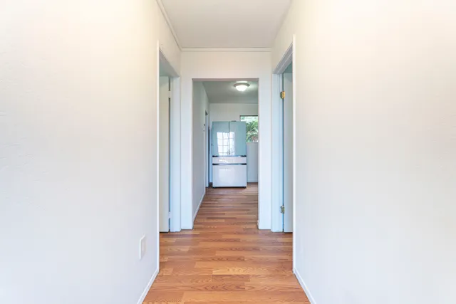 a view of a hallway with wooden floor and a bathroom