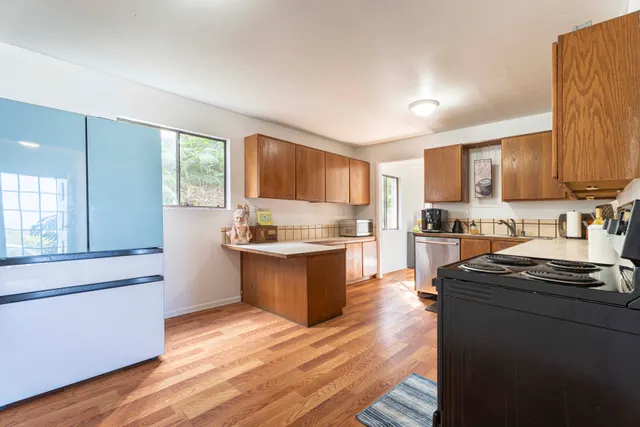 a kitchen with granite countertop wooden floors stainless steel appliances and sink