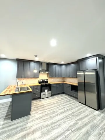a kitchen with stainless steel appliances kitchen island granite countertop a refrigerator and a sink