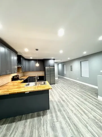 a living room with stainless steel appliances kitchen island granite countertop a sink and cabinets