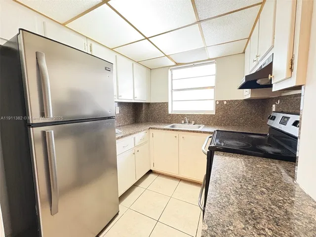 a kitchen with granite countertop a refrigerator and a sink