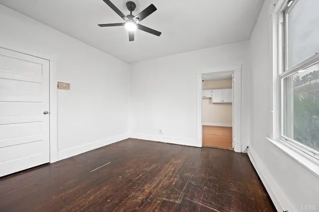 an empty room with wooden floor cabinet and windows