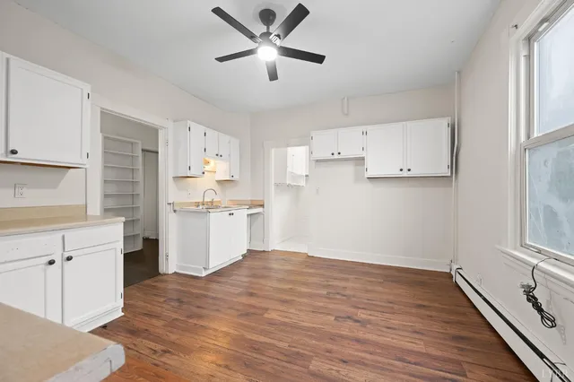 a kitchen with cabinets wooden floor and stainless steel appliances