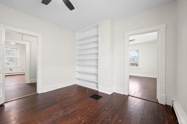 an empty room with wooden floor cabinet and windows