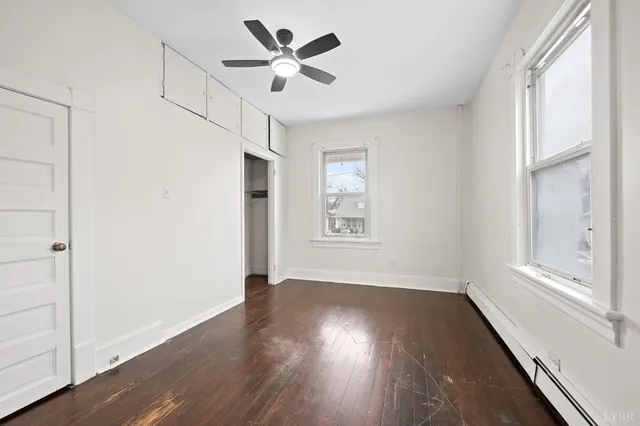 a view of empty room with wooden floor and fan