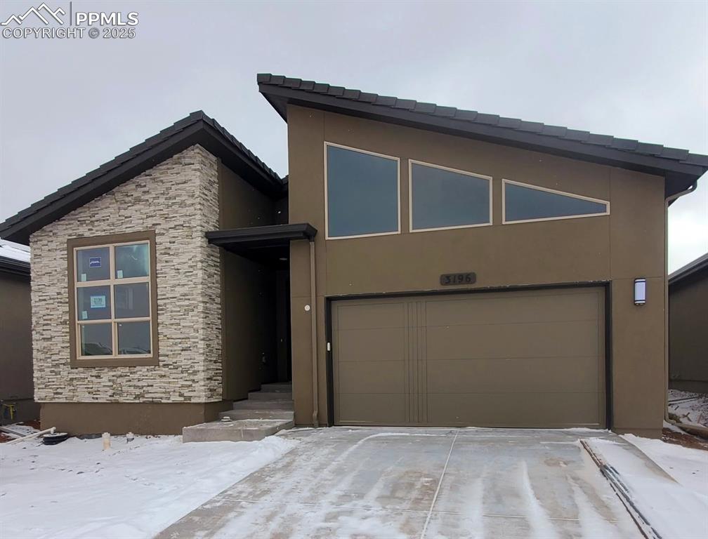 3196 Virga Loop Colorado Springs, CO 80904 - Photo 1 of 1 Contemporary house with stucco siding, stone siding, driveway, and an attached garage