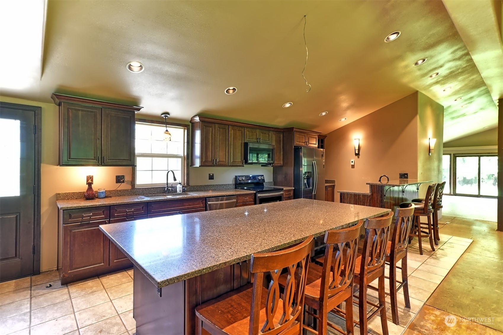 23720 Locust Way Bothell, WA 98021 - Photo 3 of 30 a kitchen with stainless steel appliances kitchen island granite countertop a table chairs sink and cabinets