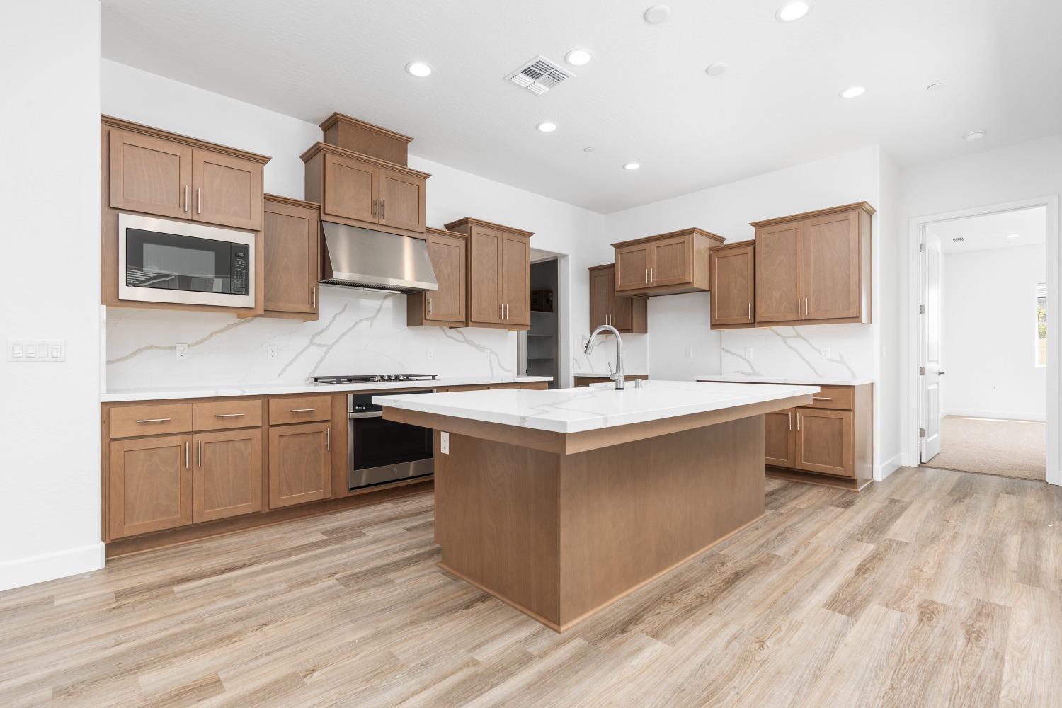 276 Huckleberry Lane South Madera, CA 93636 - Photo 5 of 32 a kitchen with stainless steel appliances kitchen island granite countertop a sink and wooden cabinets