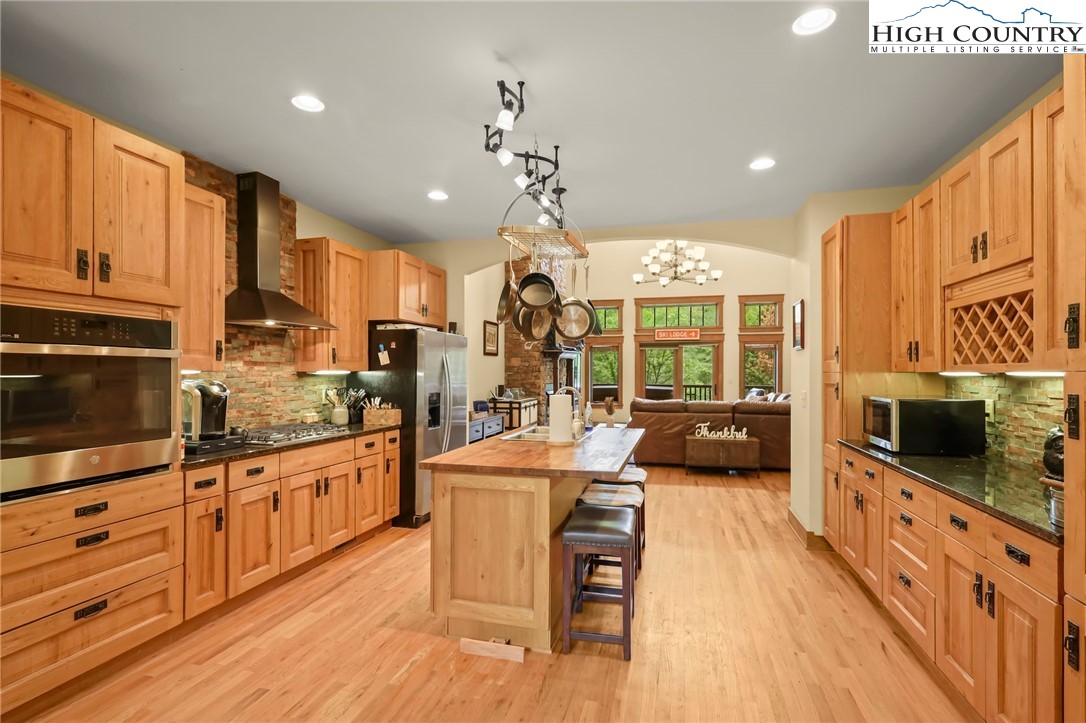 138 South Camp Road, Unit 103 Boone, NC 28607 - Photo 10 of 50 a kitchen with stainless steel appliances kitchen island granite countertop a stove a sink dishwasher a dining table and chairs with wooden floor