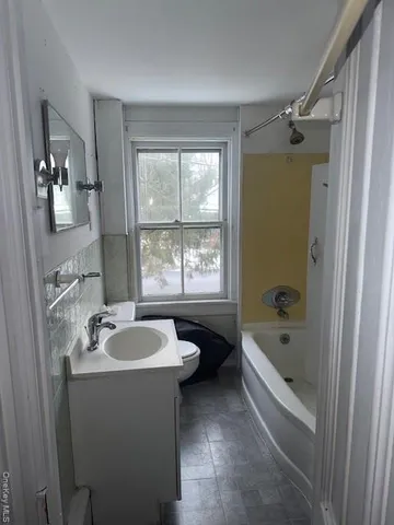 a bathroom with a tub a sink a window and a shower