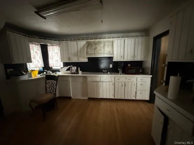 a kitchen with stainless steel appliances a sink wooden floor cabinets and a window