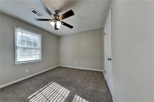 an empty room with ceiling fan and windows