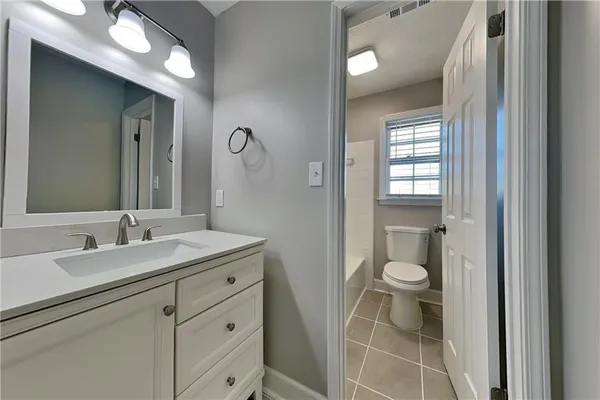 a bathroom with a granite countertop sink a toilet and a mirror