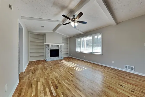 a view of empty room with wooden floor and fan