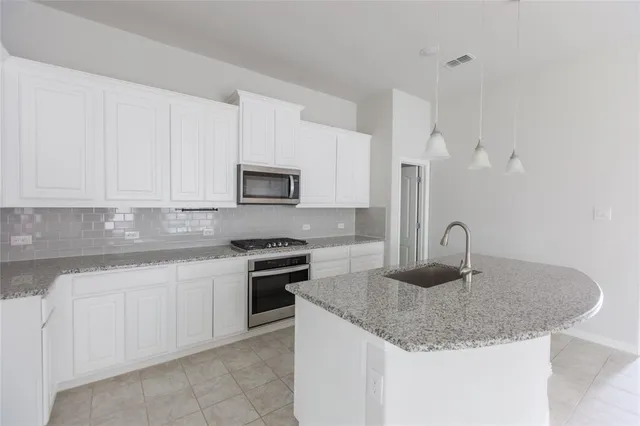 a kitchen with granite countertop a sink dishwasher stove and white cabinets