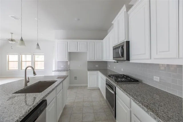 a kitchen with stainless steel appliances granite countertop a sink stove and cabinets
