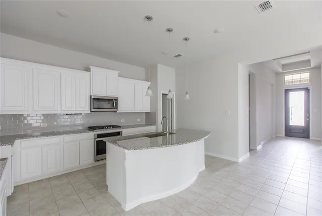 a kitchen with stainless steel appliances granite countertop a sink and white cabinets