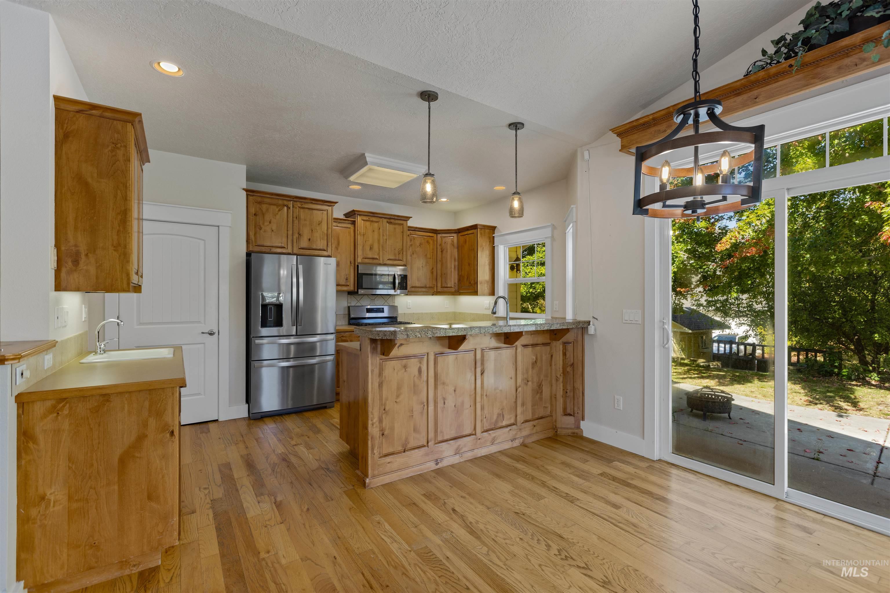 5426 West School Ridge Road Boise, ID 83714 - Photo 21 of 39 Wood-finish flooring throughout, full kitchen with stainless steel appliances, granite countertops, and wood cabinetry