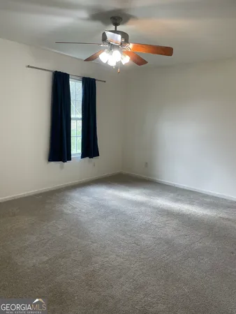 a view of an empty room with window and chandelier fan