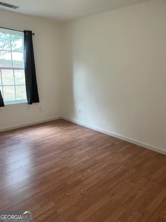 a view of an empty room with wooden floor and a window