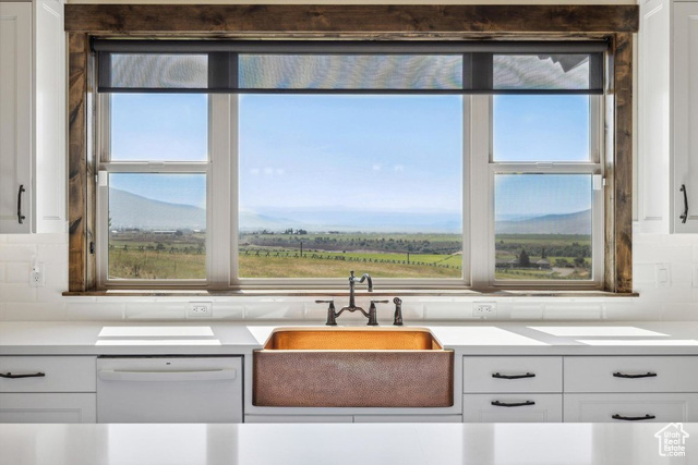 6117 North Rocky Ridge Road Peoa, UT 84061 - Photo 41 of 83 Kitchen featuring sink, white dishwasher, a mountain view, decorative backsplash, and white cabinets