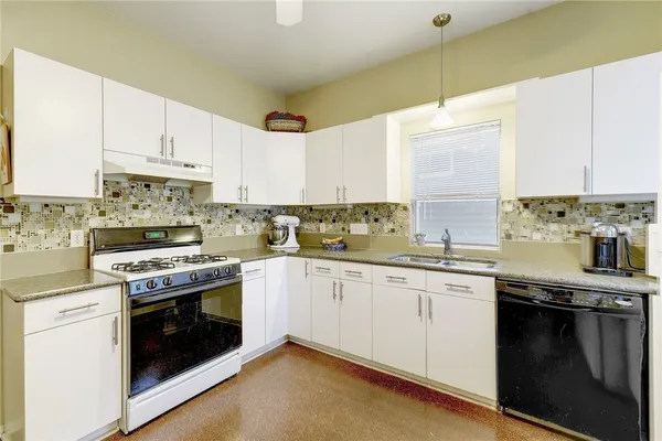 a kitchen with granite countertop white cabinets and stainless steel appliances