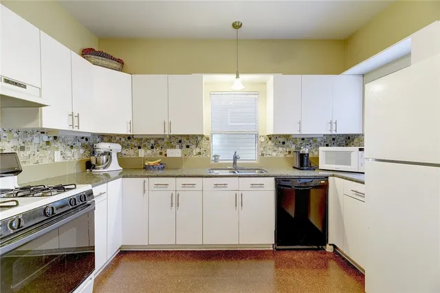 a kitchen with stainless steel appliances a stove a sink and white cabinets