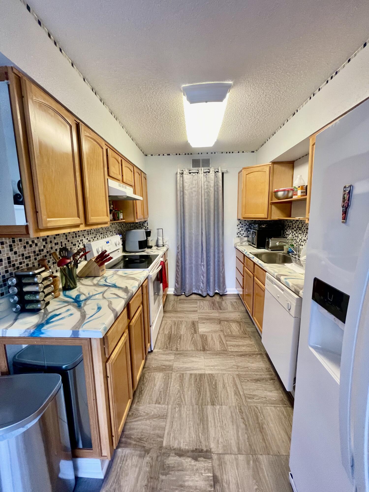 210 Pelham Road, Unit 214A Fort Walton Beach, FL 32547 - Photo 9 of 17 a kitchen with stainless steel appliances kitchen island granite countertop a stove a sink and a refrigerator