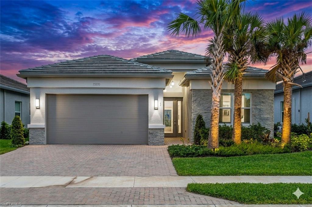 12370 Purple Ficus Way Naples, FL 34120 - Photo 2 of 50 Prairie-style house with stone siding, a garage, decorative driveway, and stucco siding