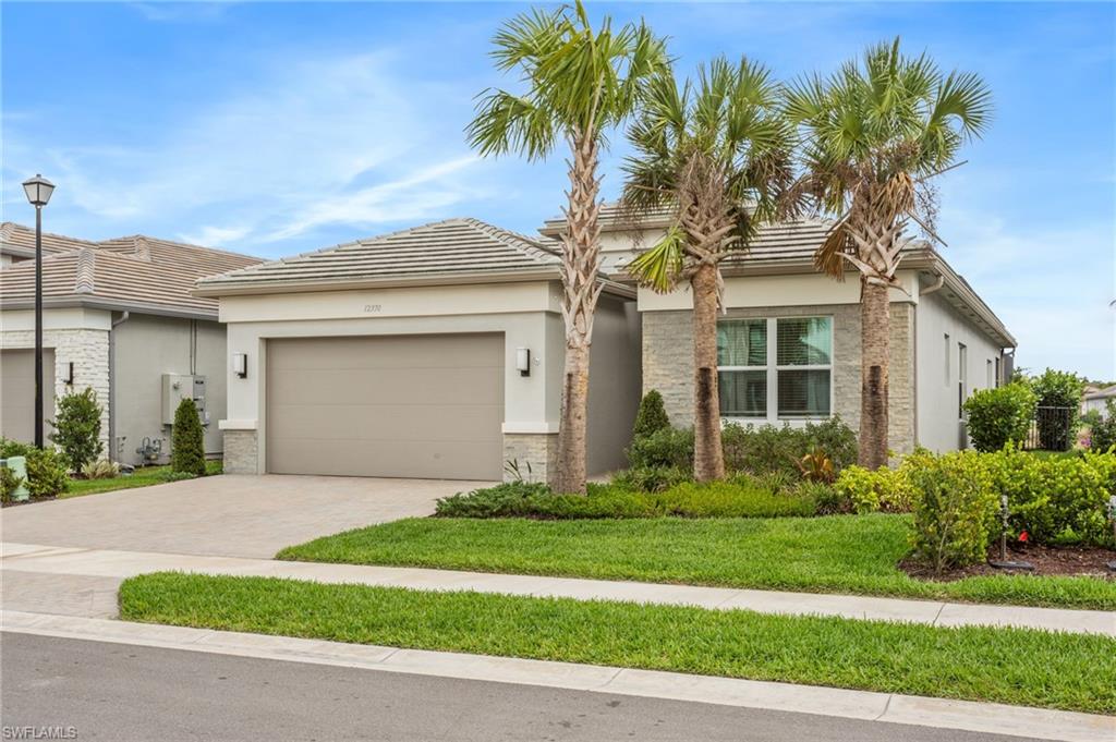 12370 Purple Ficus Way Naples, FL 34120 - Photo 3 of 50 View of front of home with decorative driveway, a garage, stucco siding, and a front yard