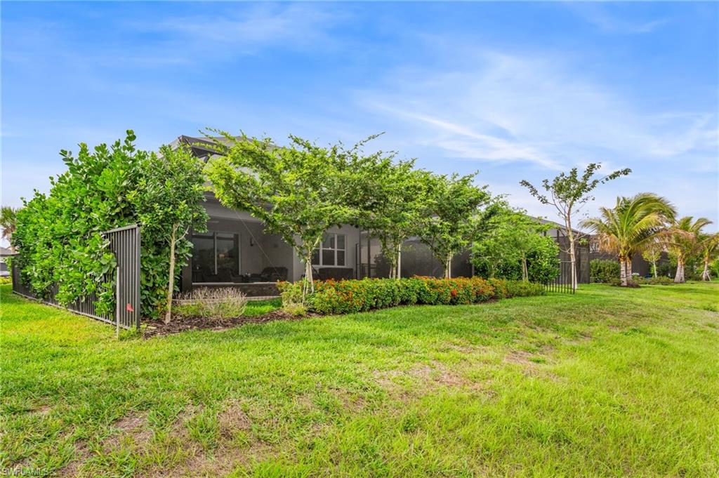 12370 Purple Ficus Way Naples, FL 34120 - Photo 34 of 50 Rear view of house featuring a yard, glass enclosure, and a sunroom