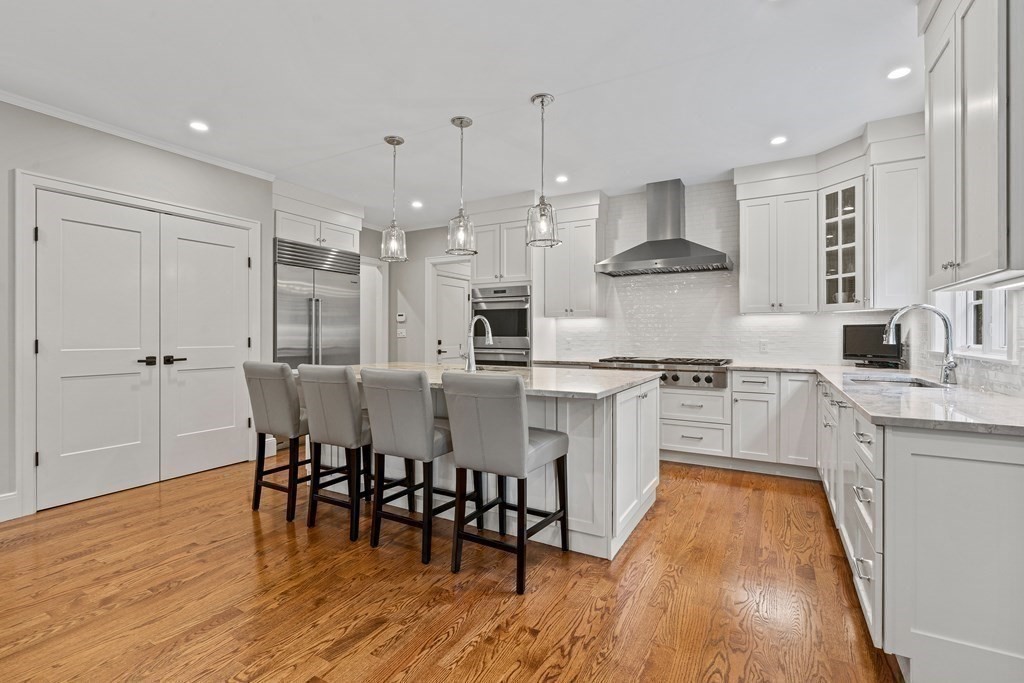 34 Willow Road Wellesley, MA 02482 - Photo 4 of 26 a kitchen with stainless steel appliances granite countertop a stove top oven a sink dishwasher and a dining table with wooden floor