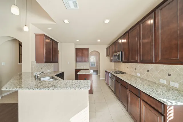 a large kitchen with stainless steel appliances granite countertop a sink stove and refrigerator