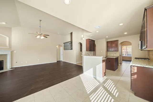 a view of a livingroom with a fireplace a ceiling fan and windows