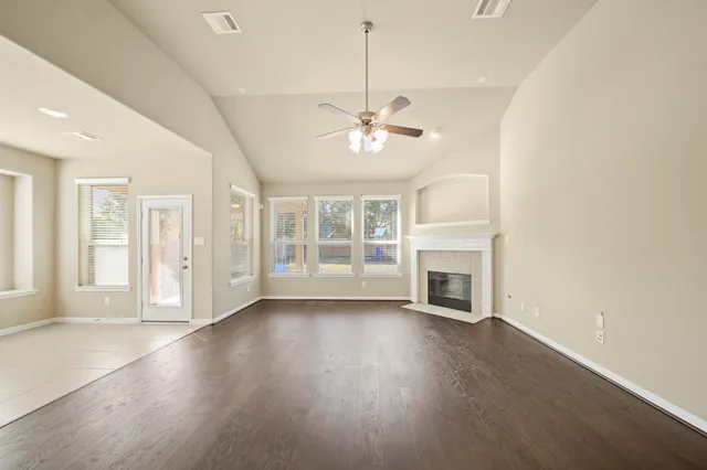 a view of an empty room with wooden floor and a kitchen