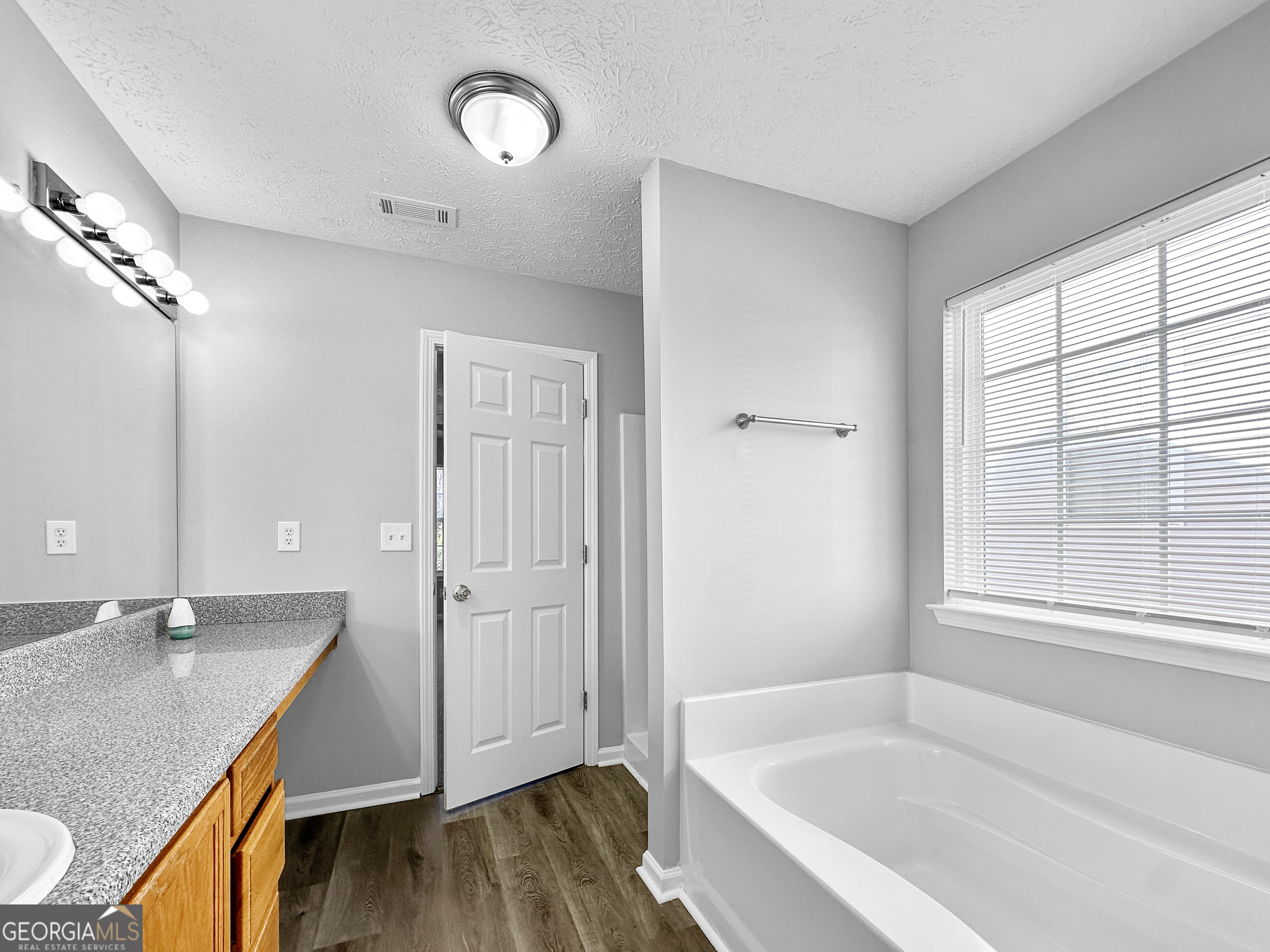 4045 Springvale Way McDonough, GA 30252 - Photo 11 of 18 a bathroom with a granite countertop sink a mirror and a bathtub