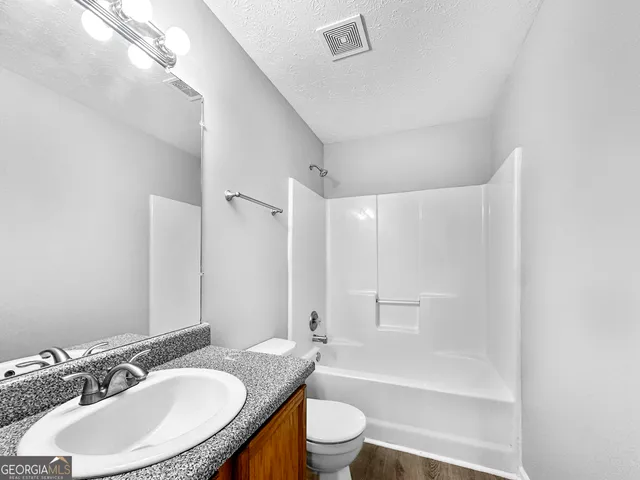 a bathroom with a granite countertop sink toilet a mirror and shower