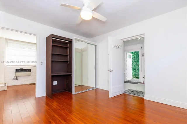a view of empty room with wooden floor and kitchen view