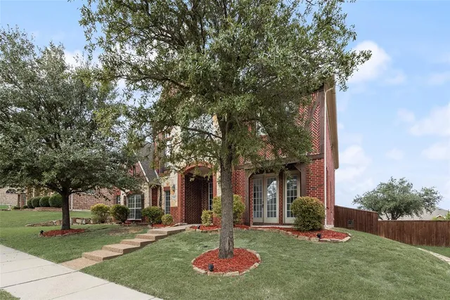 a front view of a house with garden and trees