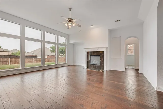 an empty room with wooden floor fireplace and windows