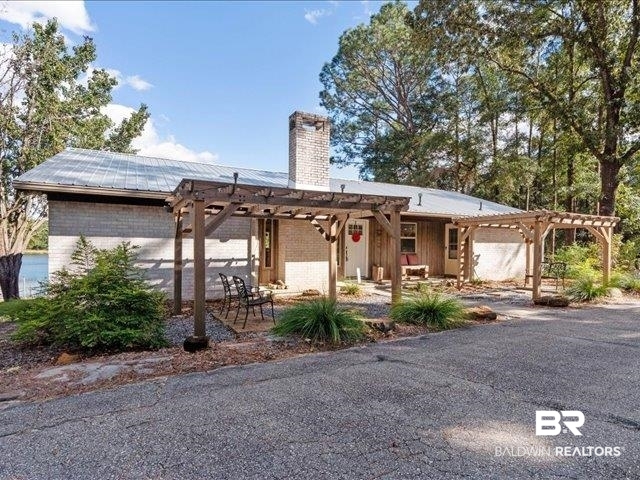 4650 Wiggins Lane Wilmer, AL 36587 - Photo 2 of 66 View of front of property with a pergola, brick siding, a chimney, and a metal roof