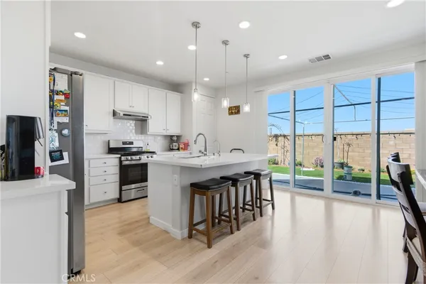 a kitchen with kitchen island granite countertop a stove a sink a refrigerator and a dining table with wooden floor