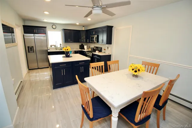 a kitchen with stainless steel appliances granite countertop a sink a stove a refrigerator with a dining table and chairs