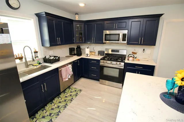 a kitchen with stainless steel appliances granite countertop wooden cabinets a stove a sink and a microwave