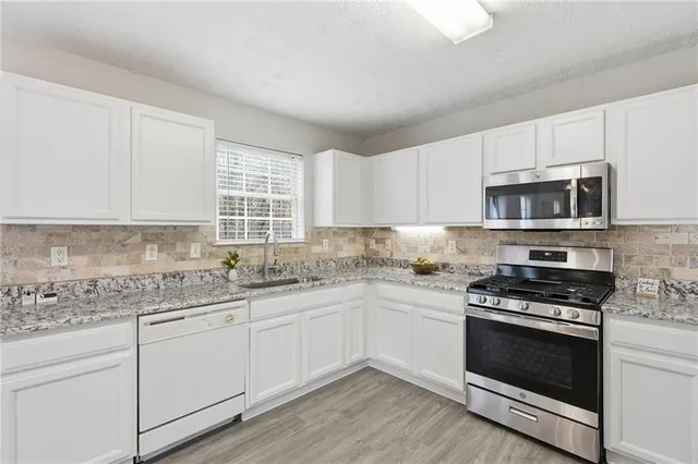 a kitchen with granite countertop a stove a sink and wooden cabinets