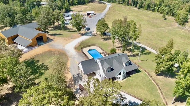 an aerial view of a house with swimming pool and large trees