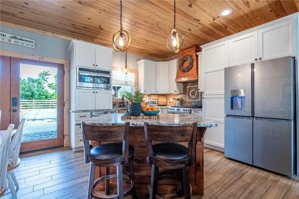a kitchen with stainless steel appliances granite countertop a table chairs refrigerator and wooden floor